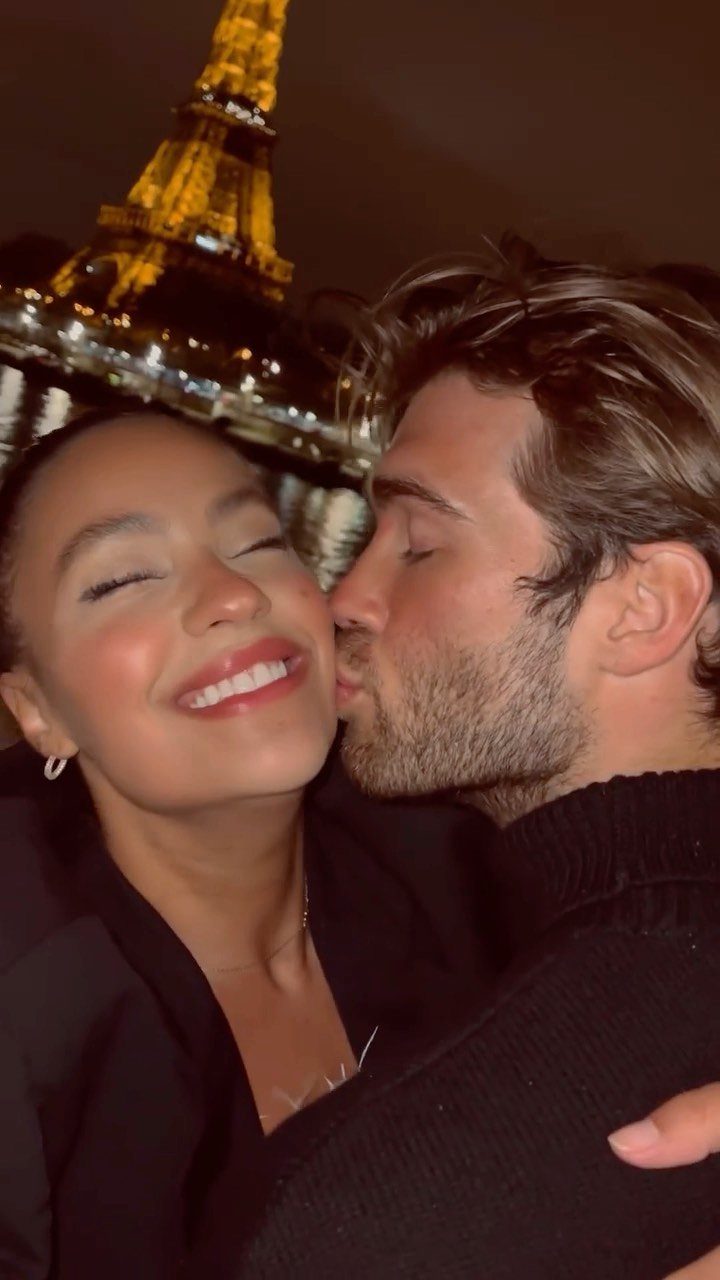 Man kissing woman on the cheek with the Eiffel Tower in the background.