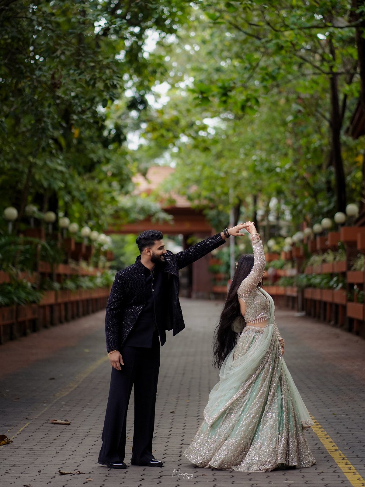 Couple dancing on a tree-lined path with the man spinning the woman around.
