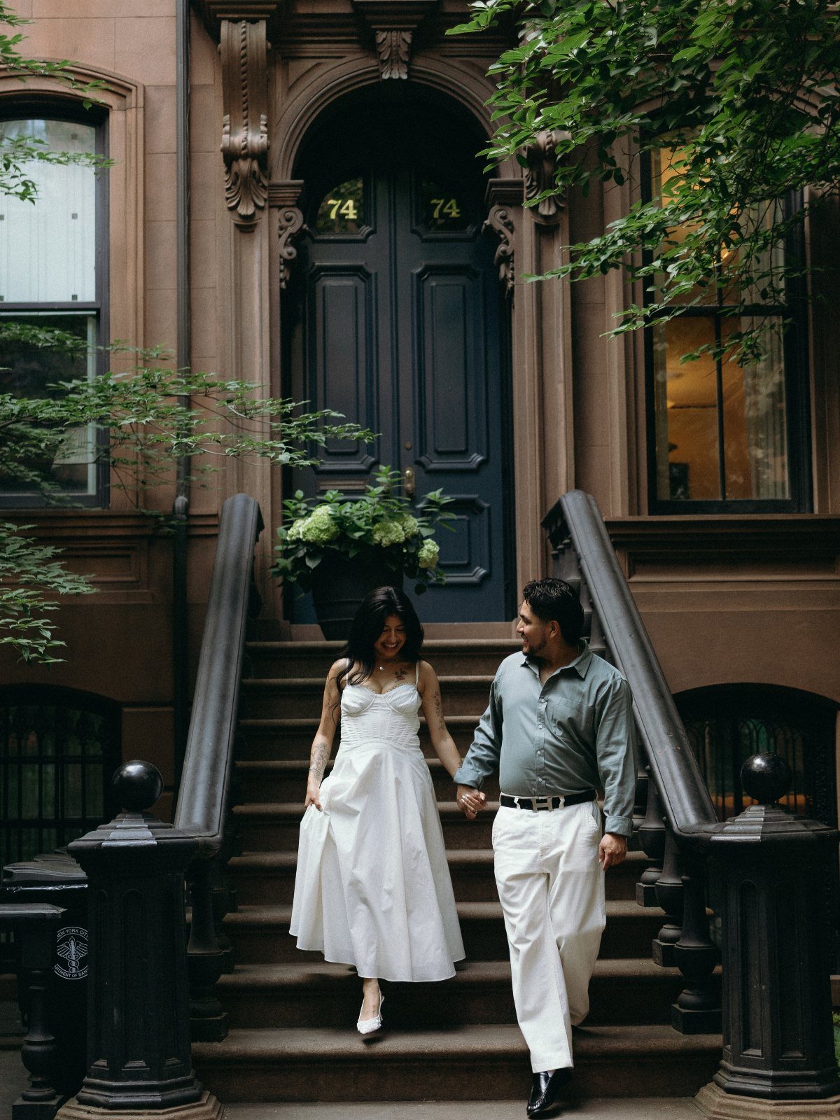 Couple holding hands walking down brownstone steps in New York City