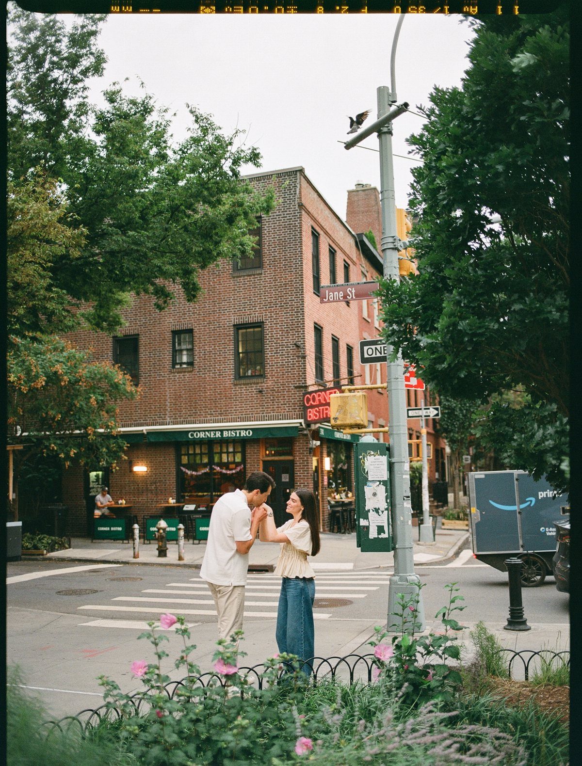 Couple holding hands on a city street corner in front of Corner Bistro.