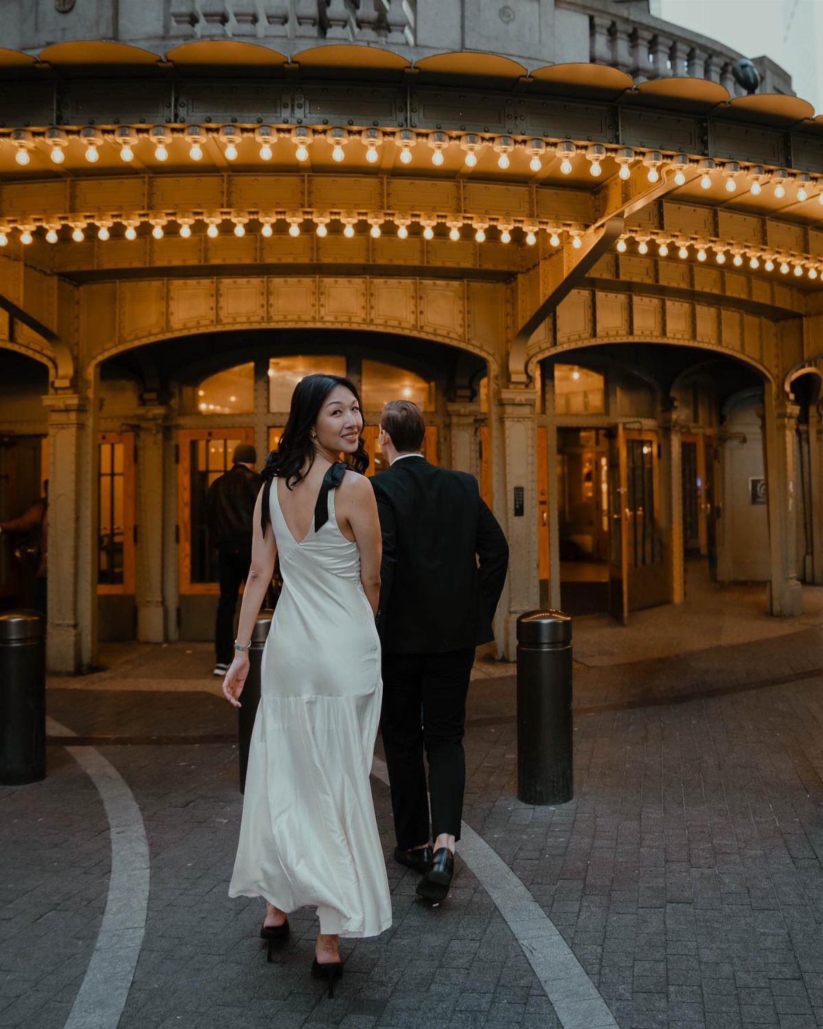 Couple in formal attire walking toward the illuminated entrance of Grand Central Terminal.