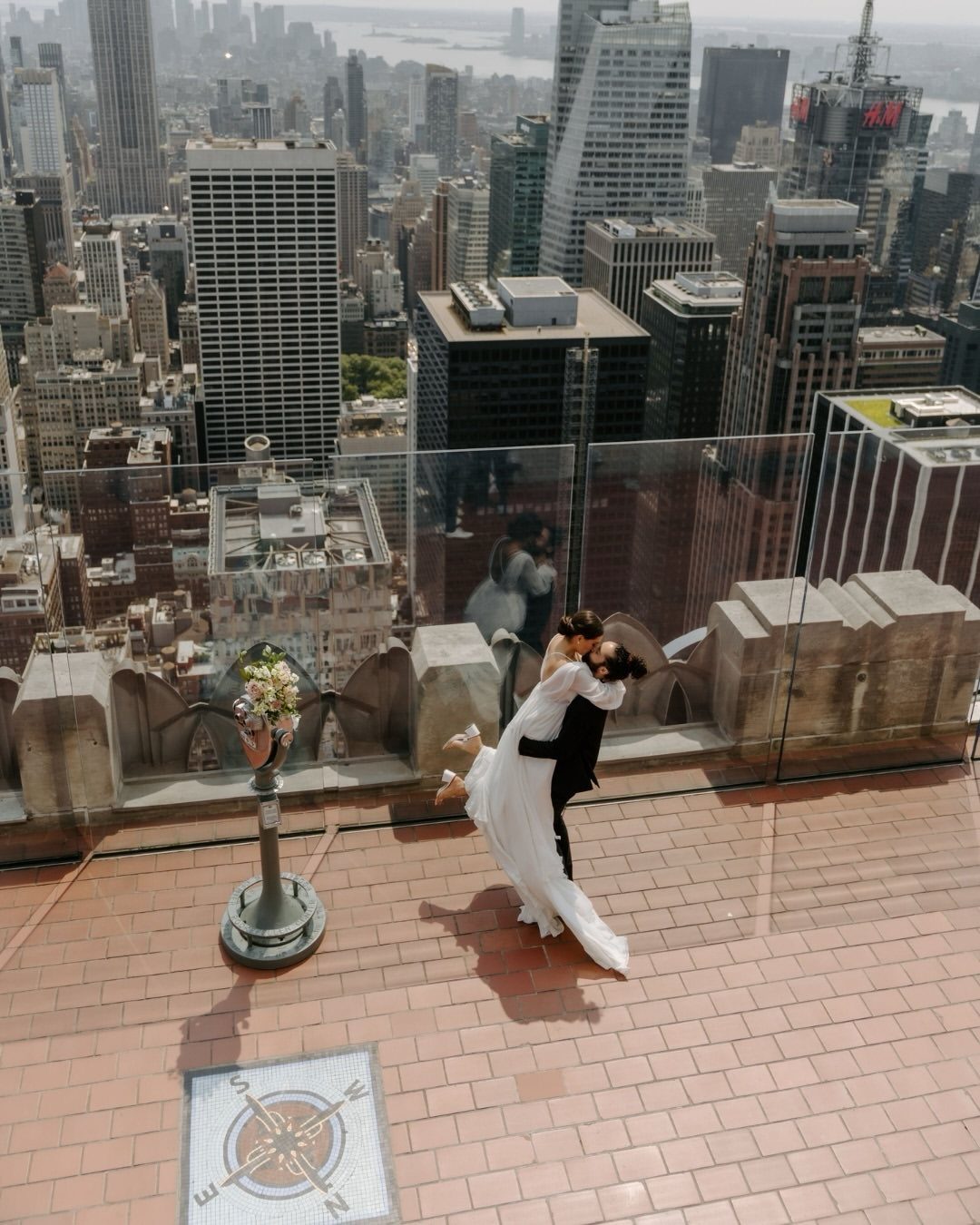 Couple in wedding attire kissing on Top of the Rock overlooking New York City.