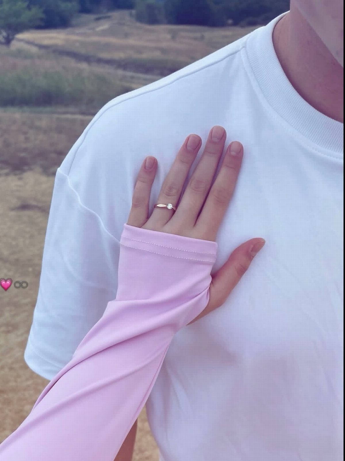 Hand with engagement ring resting on a partner's chest in a white shirt