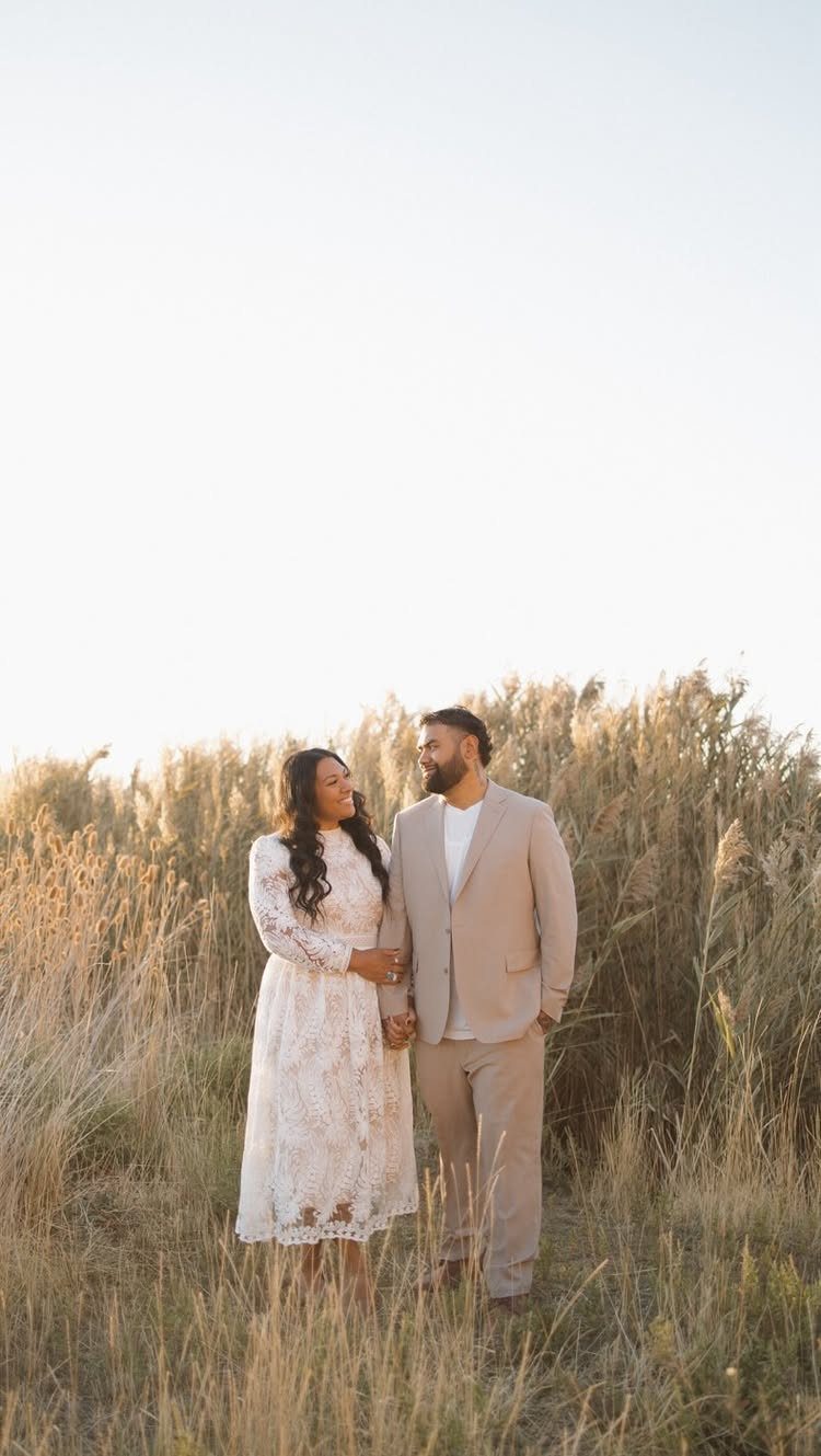 Couple in a golden field wearing a white lace dress and beige suit.