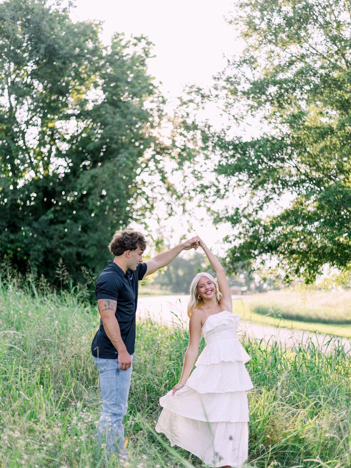 Couple dancing in a field, woman wearing a white tiered strapless maxi dress.