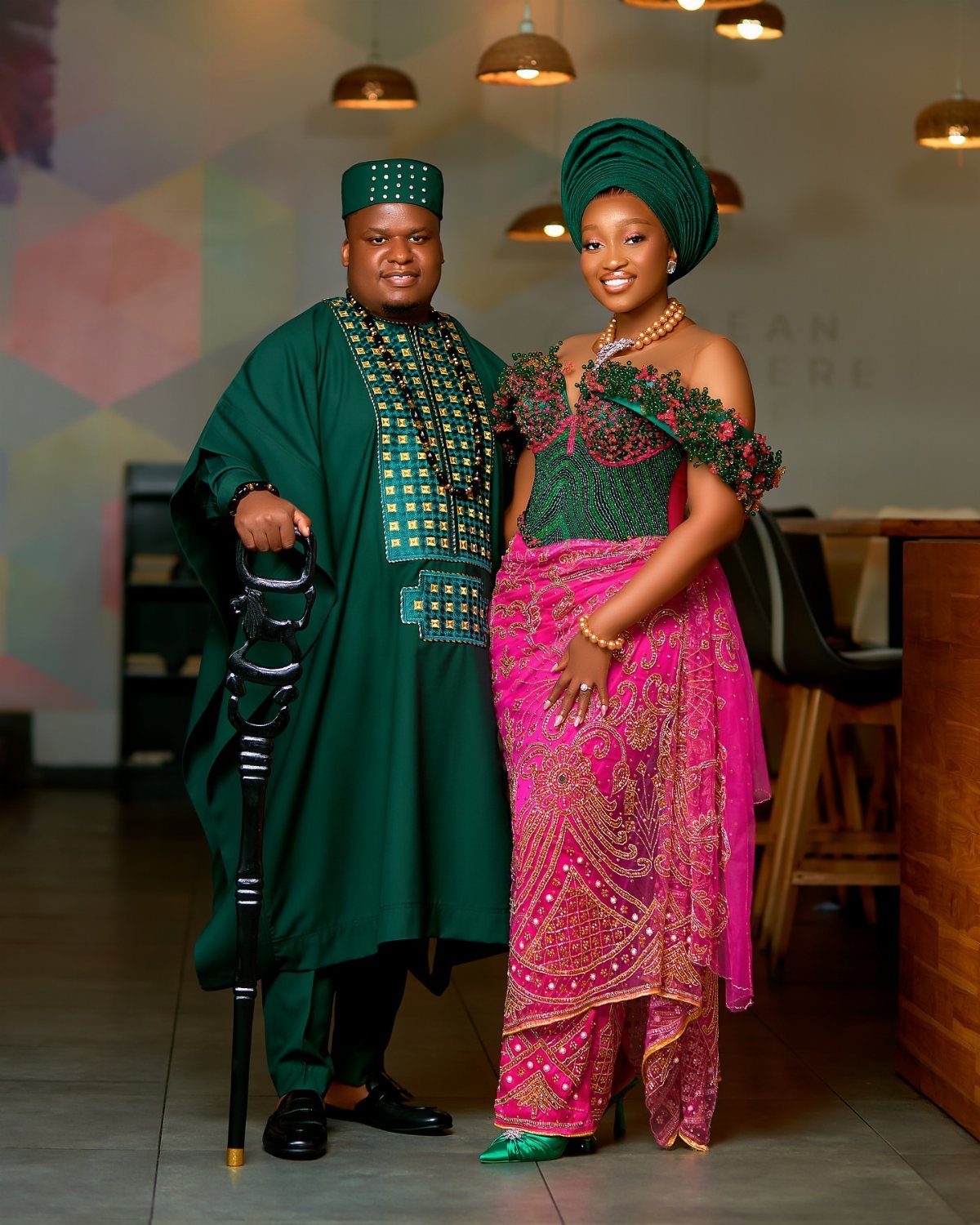 Couple in traditional Nigerian attire featuring a green agbada and pink embroidered wrapper.