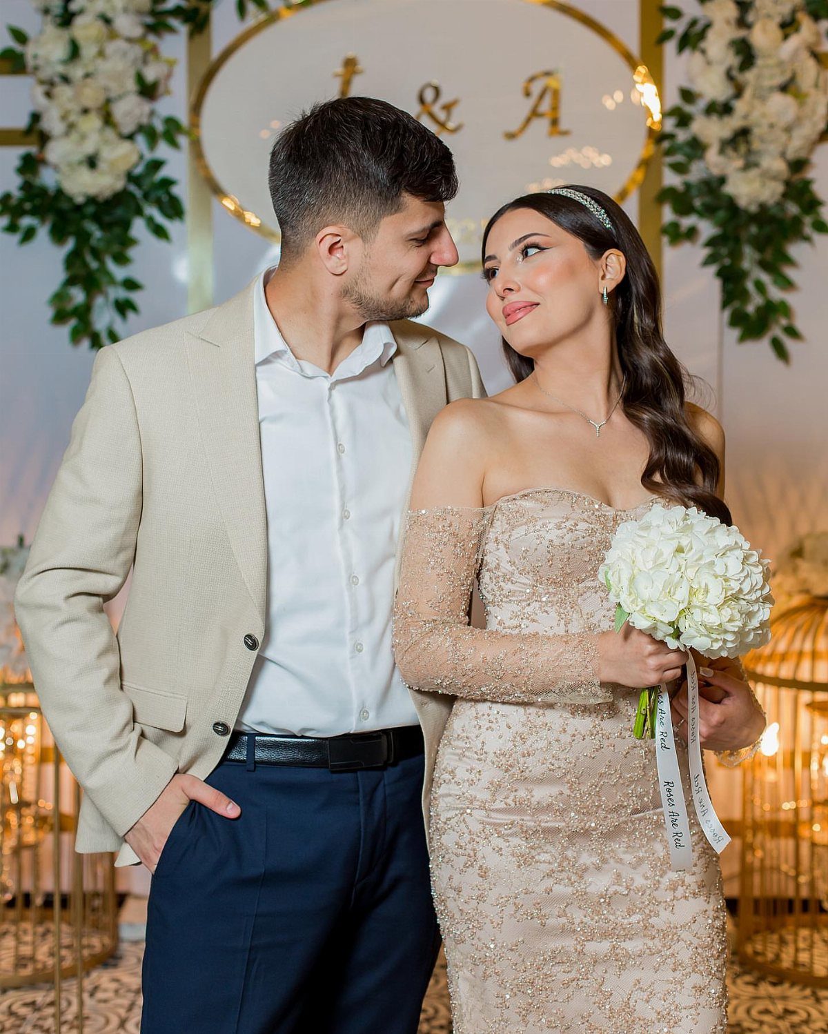Couple posing for a photo, woman wearing a sparkling champagne off-the-shoulder gown.