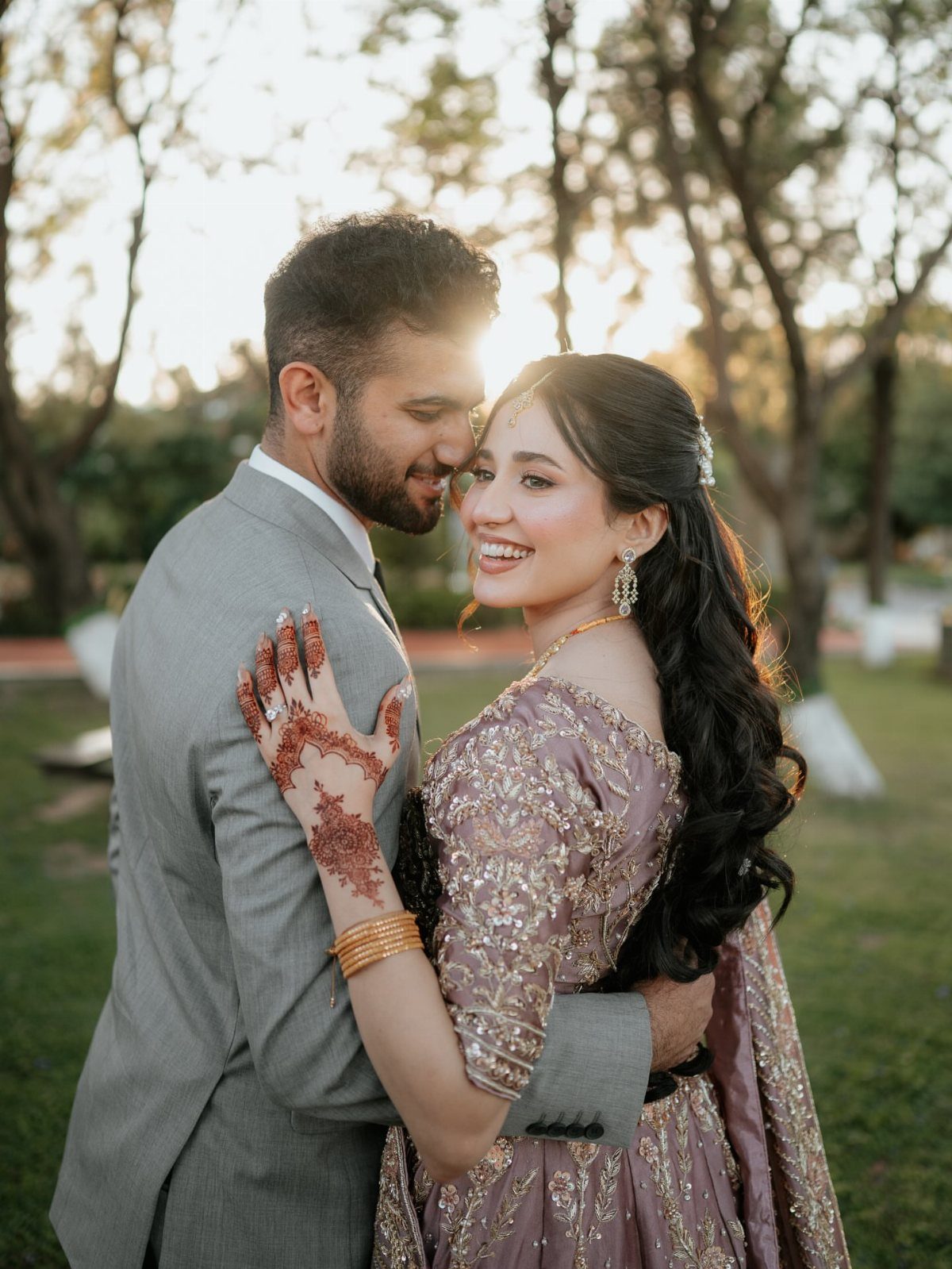 Couple embracing in a garden, woman wearing a mauve sequined dress and henna.