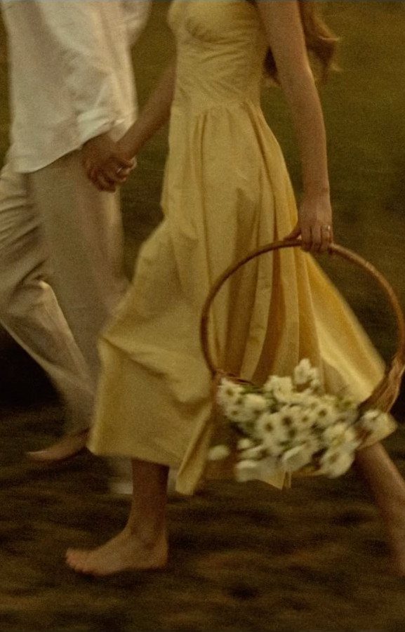 Couple walking in a field, woman in yellow dress carrying flower basket