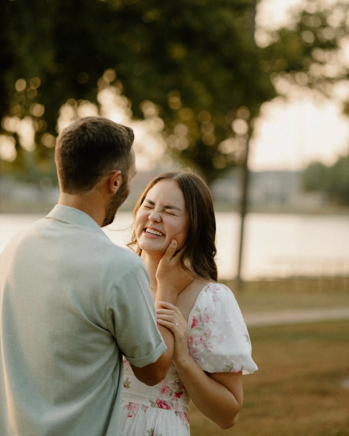 Couple embracing outdoors with the man gently touching the woman's smiling face.
