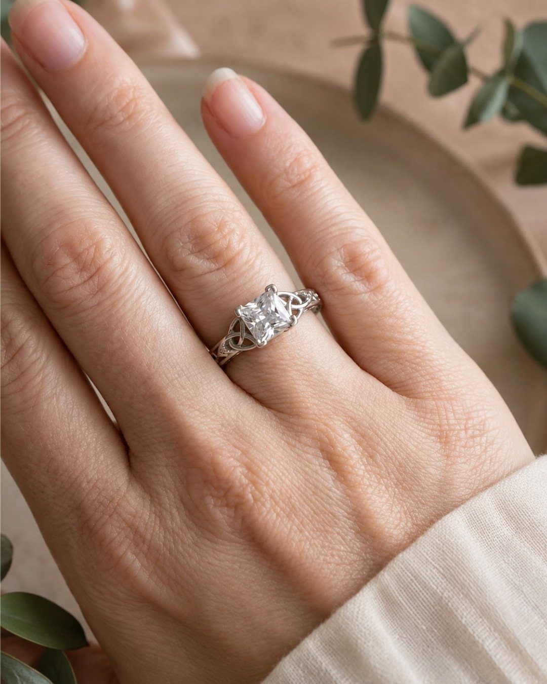 Silver engagement ring with square diamond and Celtic knot band on a finger