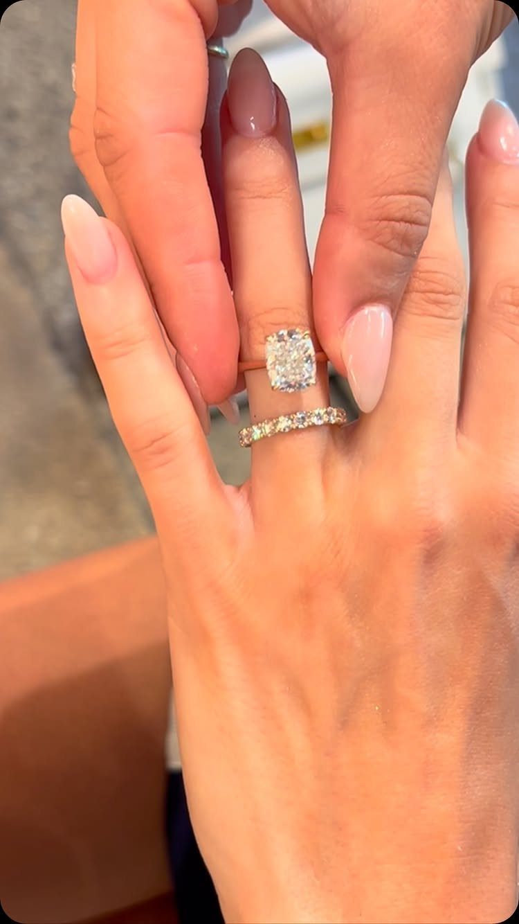 Gold eternity band and rectangular diamond engagement ring on a woman's finger