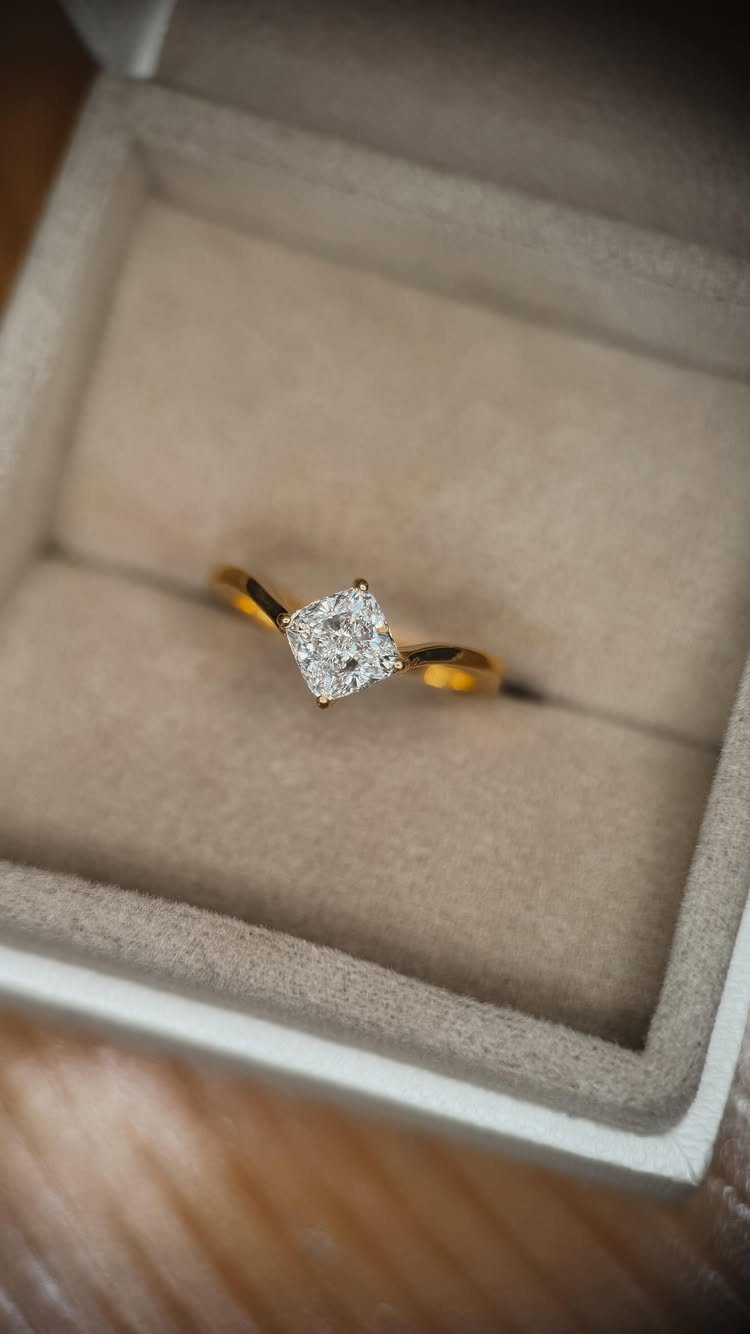 Gold engagement ring with square diamond center stone in a grey velvet box