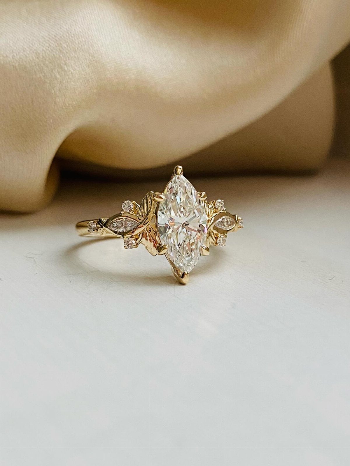 Marquise-cut diamond engagement ring with gold band on a white surface.