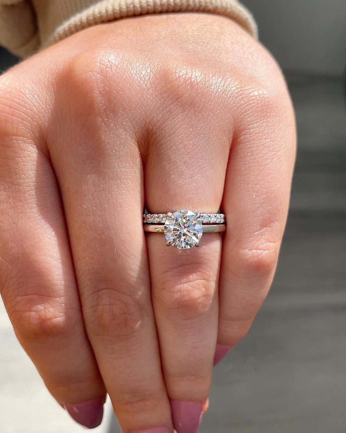 Round cut diamond engagement ring and matching band on a person's finger