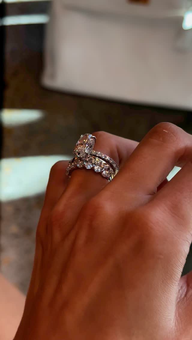 Oval diamond engagement ring and matching pavé wedding band on a woman's finger.