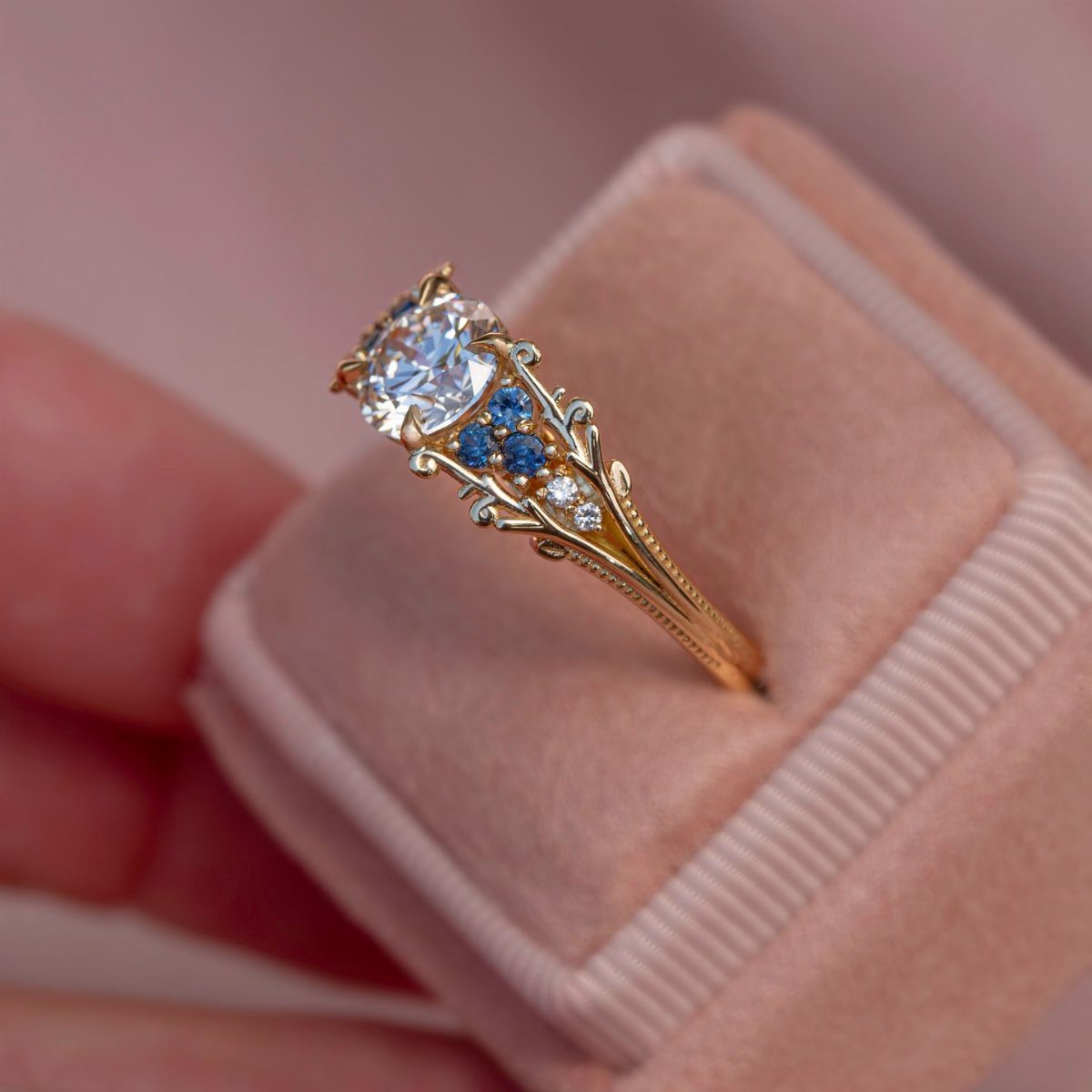 Gold vintage engagement ring with clear diamond and blue stones in pink box