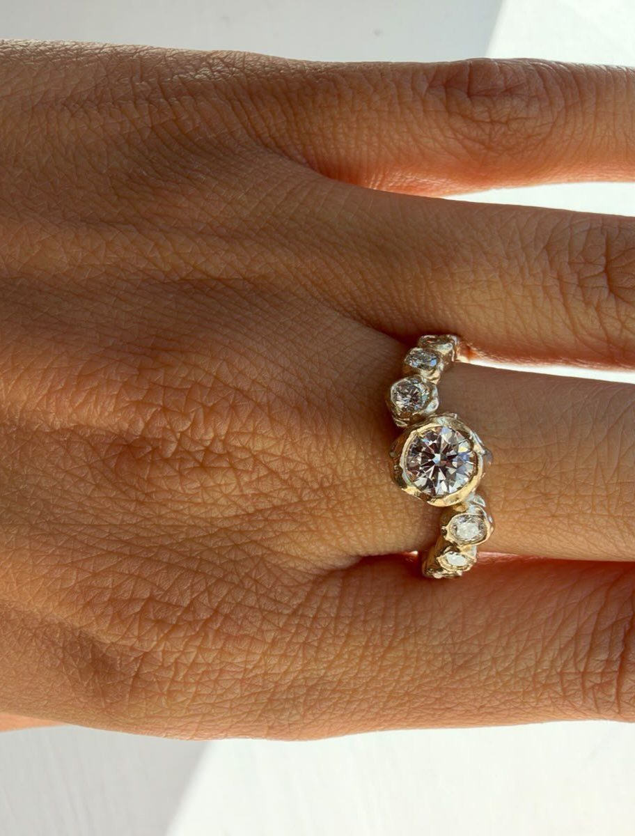 Gold engagement ring with round diamond on a person's finger