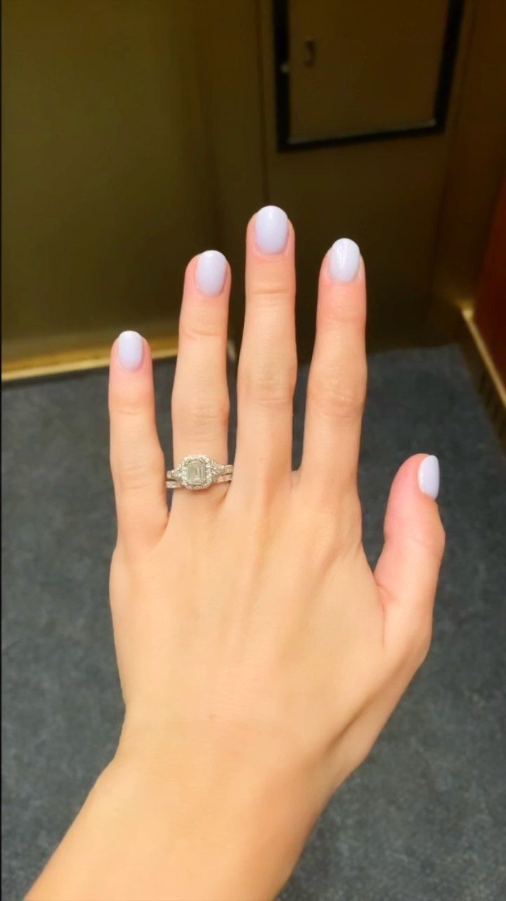 Woman's hand with purple nails wearing a square-cut diamond engagement ring.