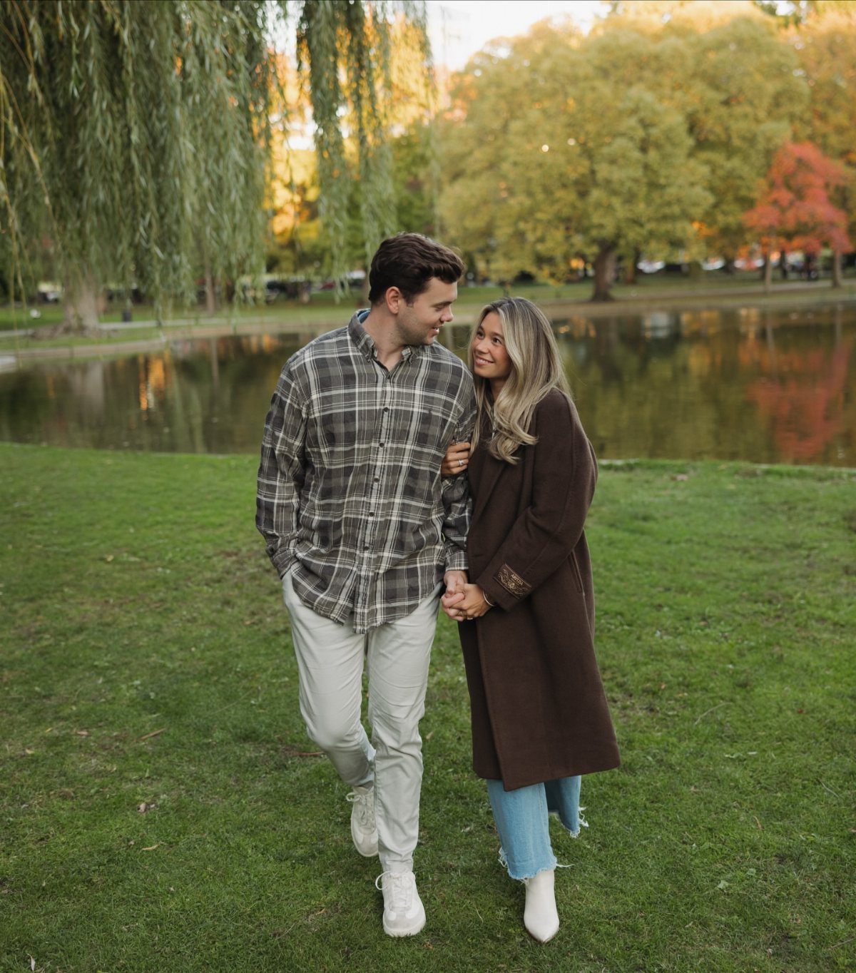 Couple walking in a park, woman wearing a long brown autumn coat.