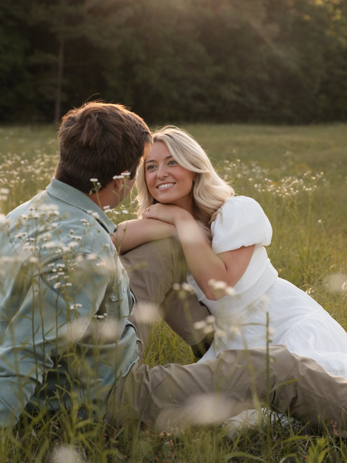 Couple in a field wearing a white dress and blue shirt for engagement photos.