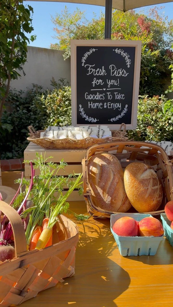 Fresh produce and bread in baskets on a table with a chalkboard sign.