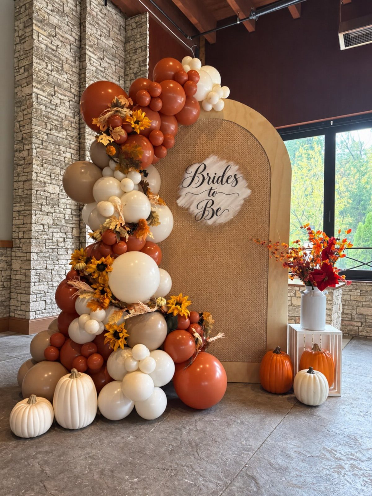 Bridal shower backdrop with orange and white balloons, sunflowers, and decorative pumpkins.