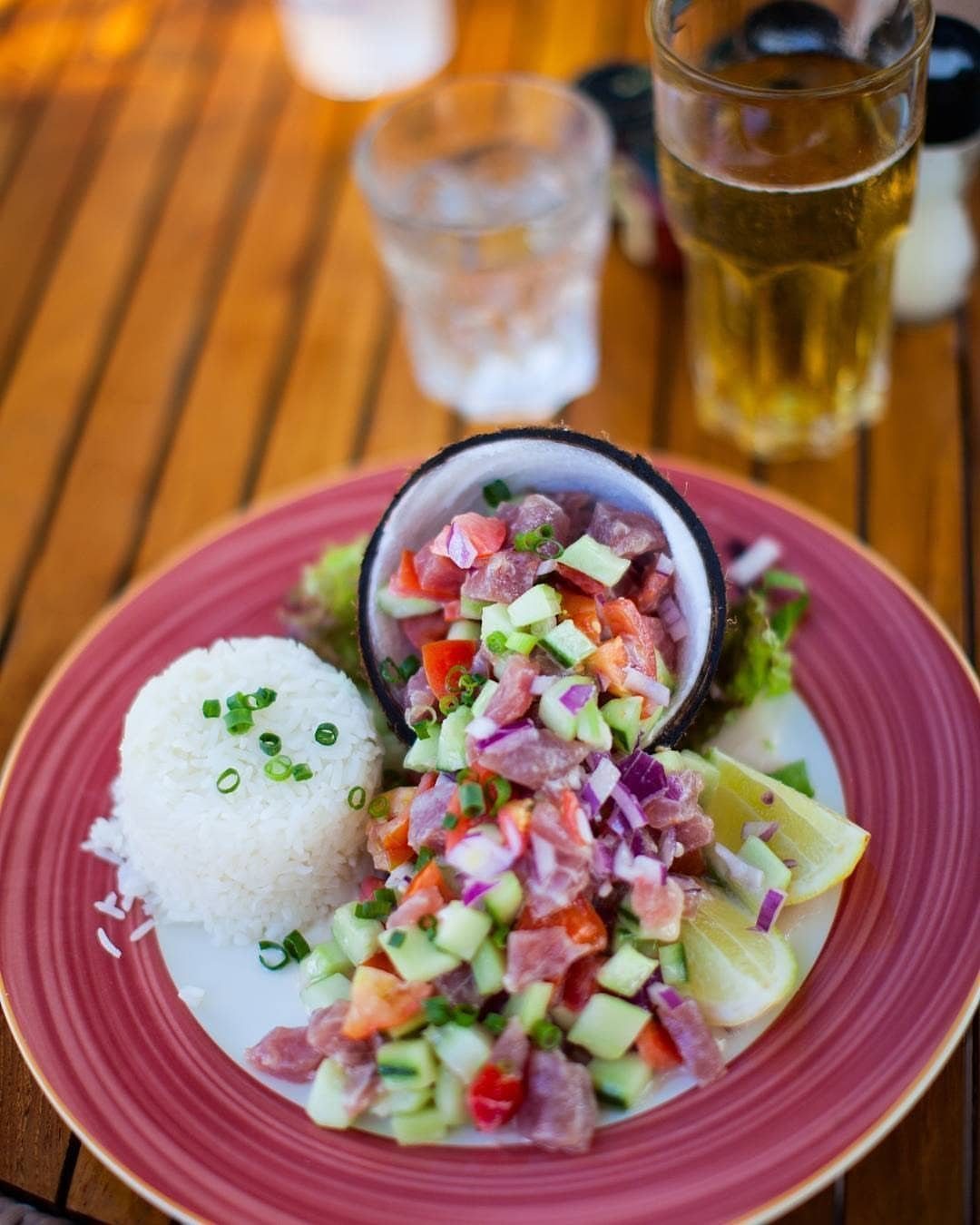 Raw fish salad with vegetables served in a coconut shell with white rice.
