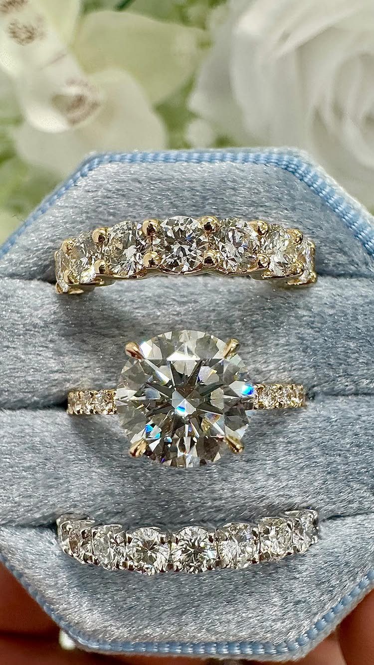 Three gold diamond rings resting in a light blue velvet jewelry box.