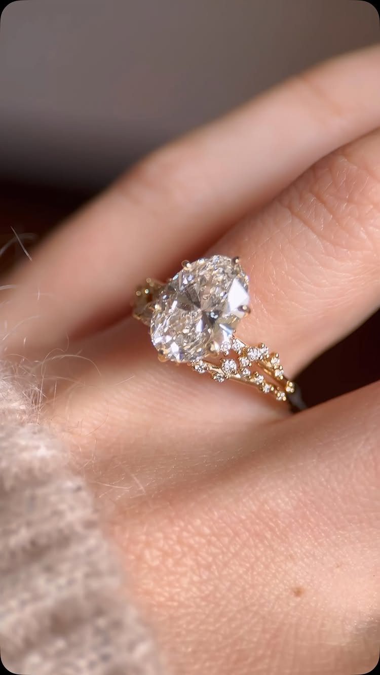 Oval-cut diamond ring and gold wedding band on a person's finger