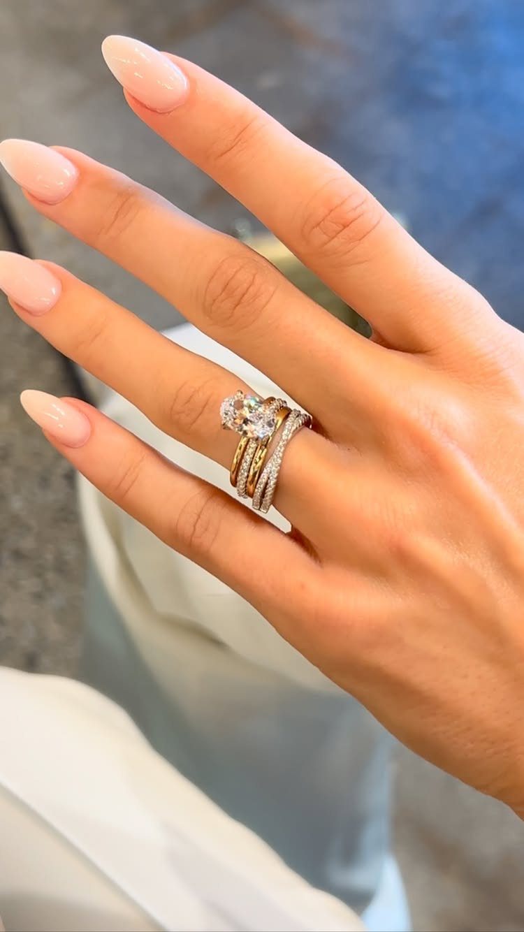 Stacked wedding rings in gold and silver tones on a woman's finger