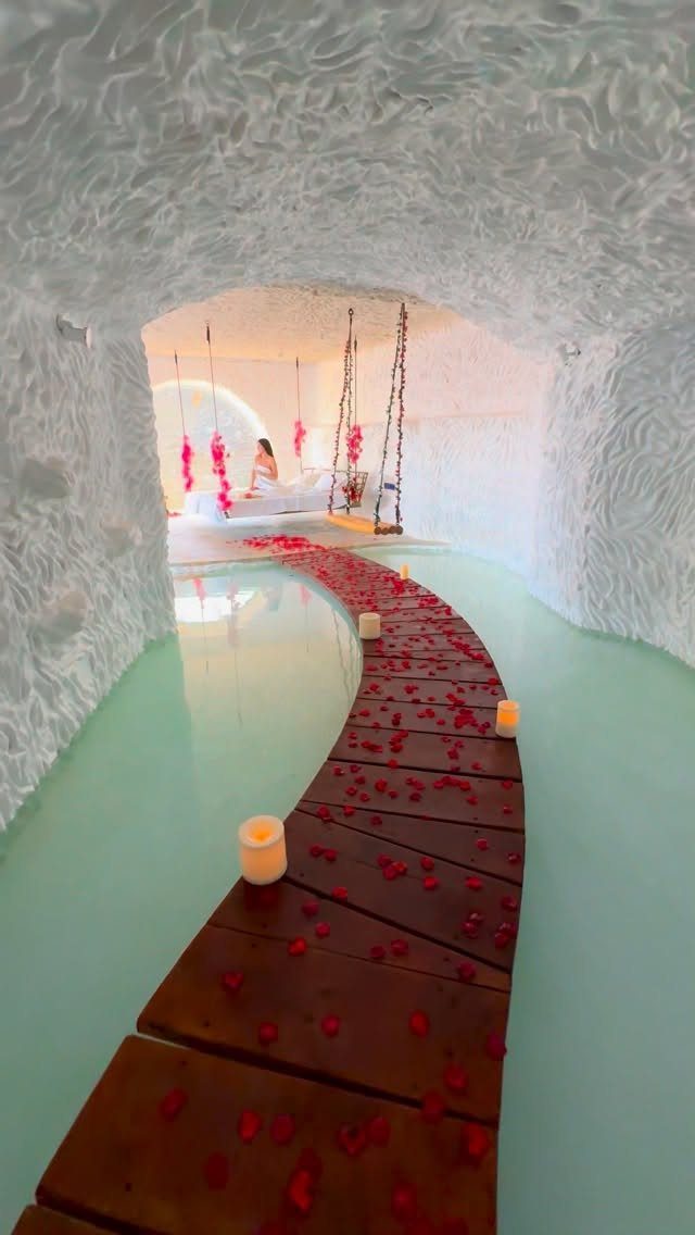 Wooden walkway with rose petals and candles inside a white textured cave resort.