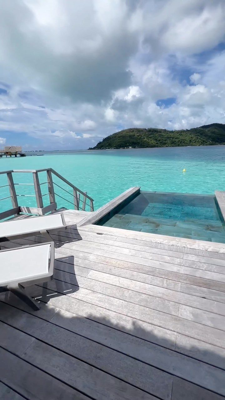 Wooden deck with infinity pool overlooking turquoise lagoon and tropical mountains in Bora Bora