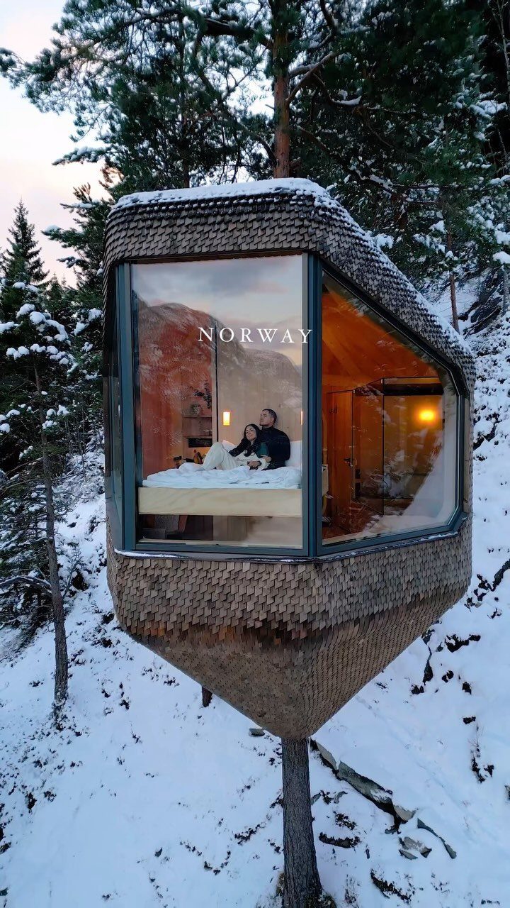 Couple relaxing in a modern treehouse cabin surrounded by snowy Norwegian pine forests