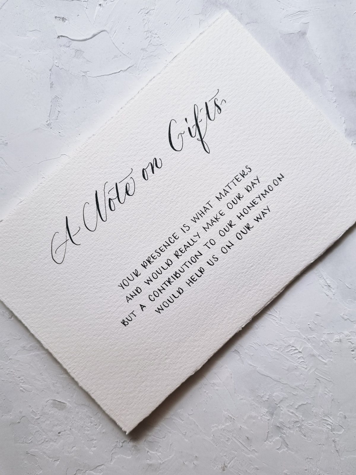 White textured card with black calligraphy requesting honeymoon fund contributions for a wedding.