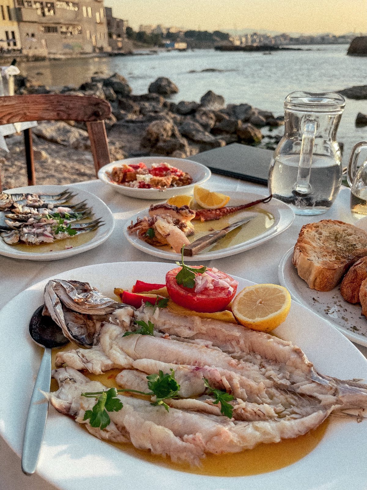 Seafood platters and bread on a table at an outdoor seaside restaurant.