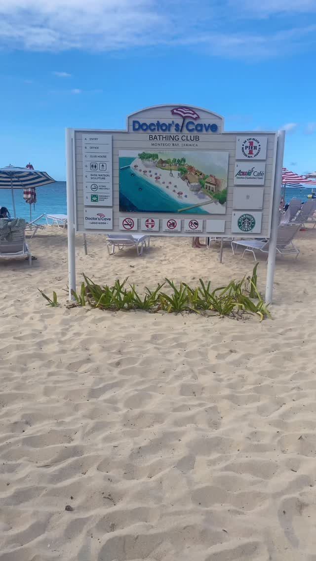 Doctor's Cave Bathing Club sign on a sandy beach with ocean in background