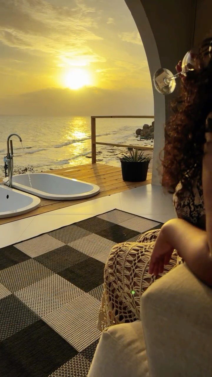 Woman watching a golden sunset over the ocean from a luxury balcony deck.