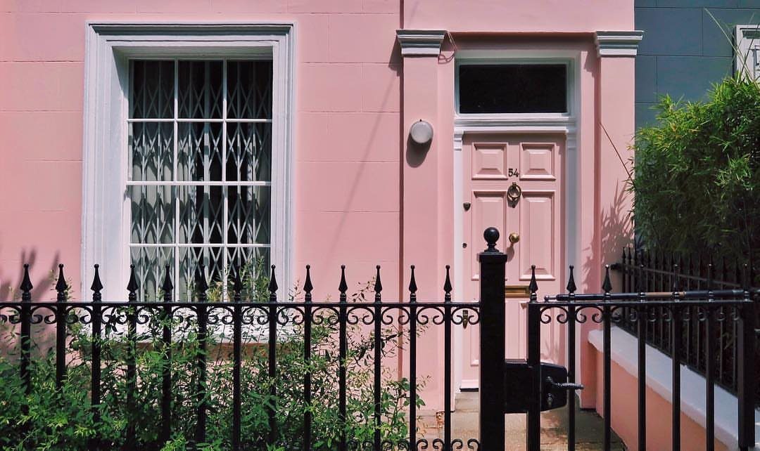 Pink house facade with white trim and black wrought iron fence in London