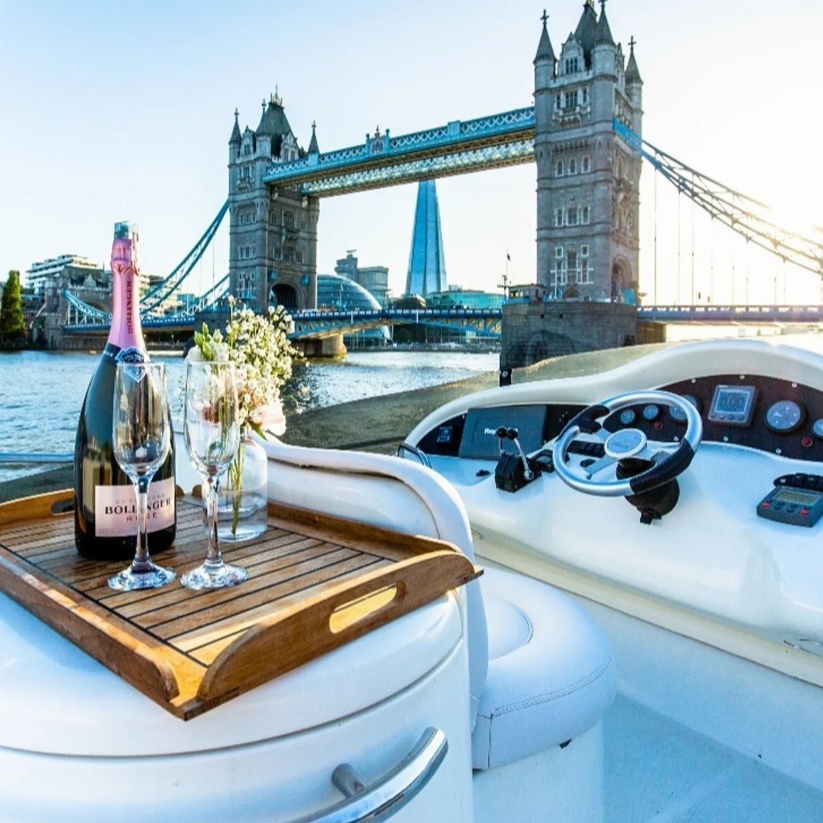 Champagne and glasses on a boat deck with Tower Bridge in the background
