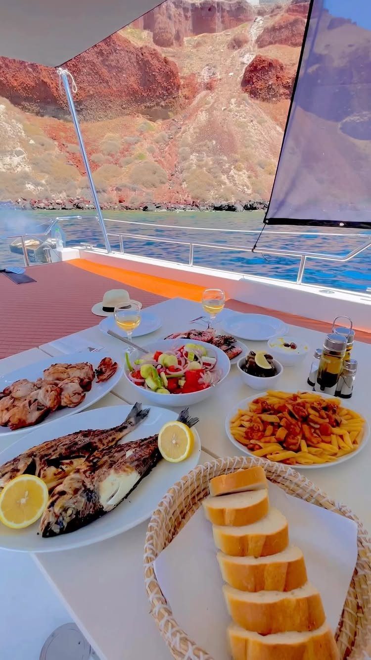 Mediterranean meal on a boat deck with volcanic cliffs and blue sea background