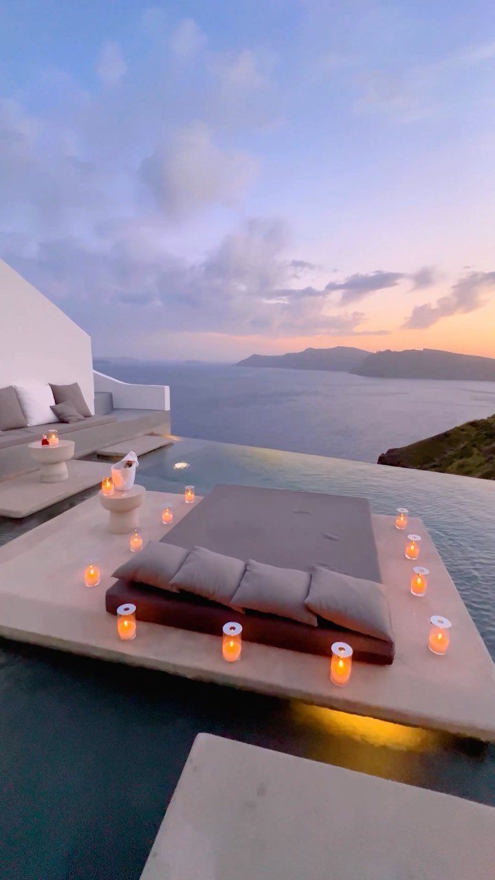 Romantic outdoor bed with candles overlooking the Santorini caldera at sunset