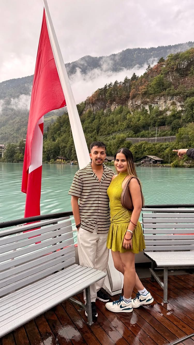 Couple posing on a boat with a Swiss flag and misty mountains behind them.