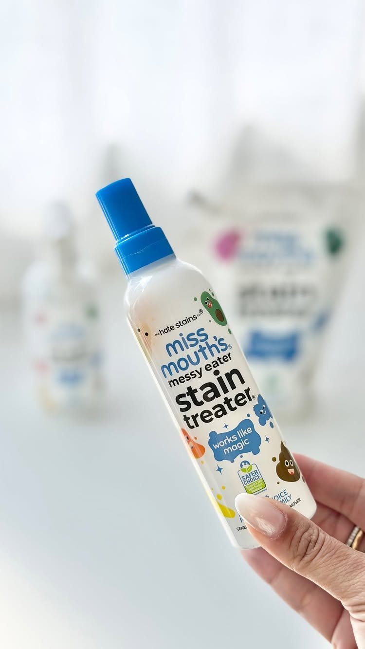 Hand holding a bottle of Miss Mouth's Messy Eater stain remover spray.