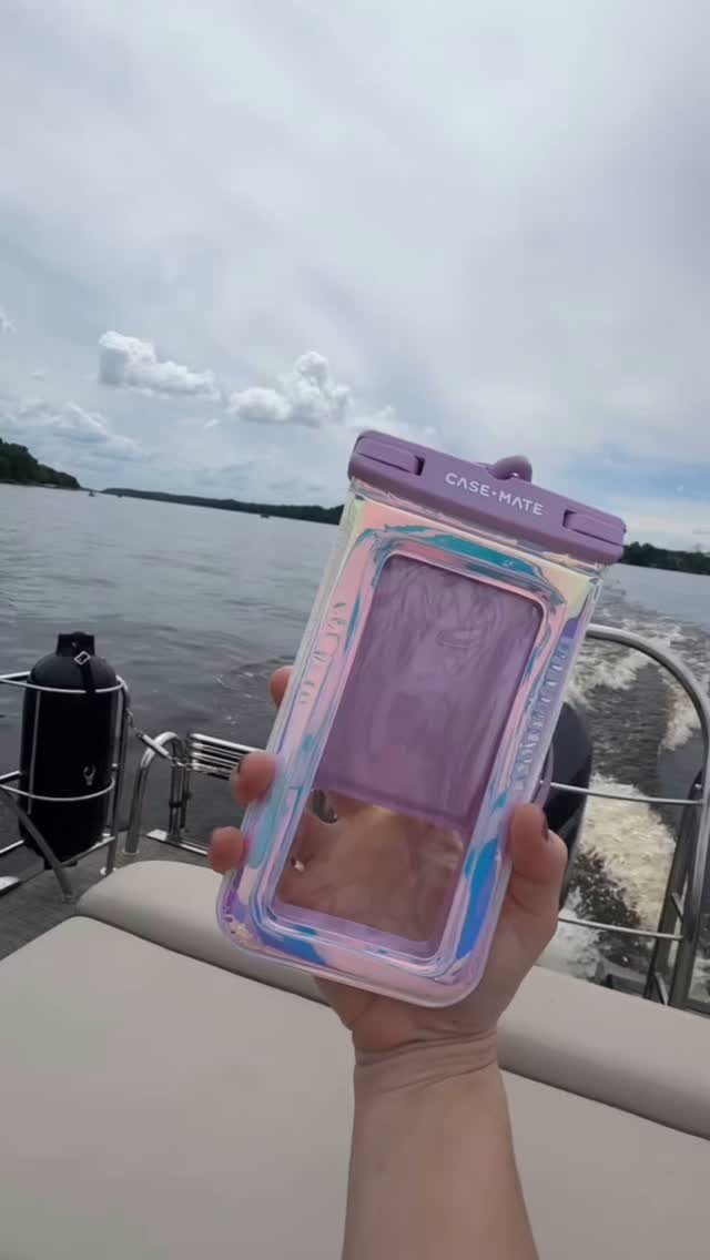 Purple waterproof phone case held up on a boat moving across a river