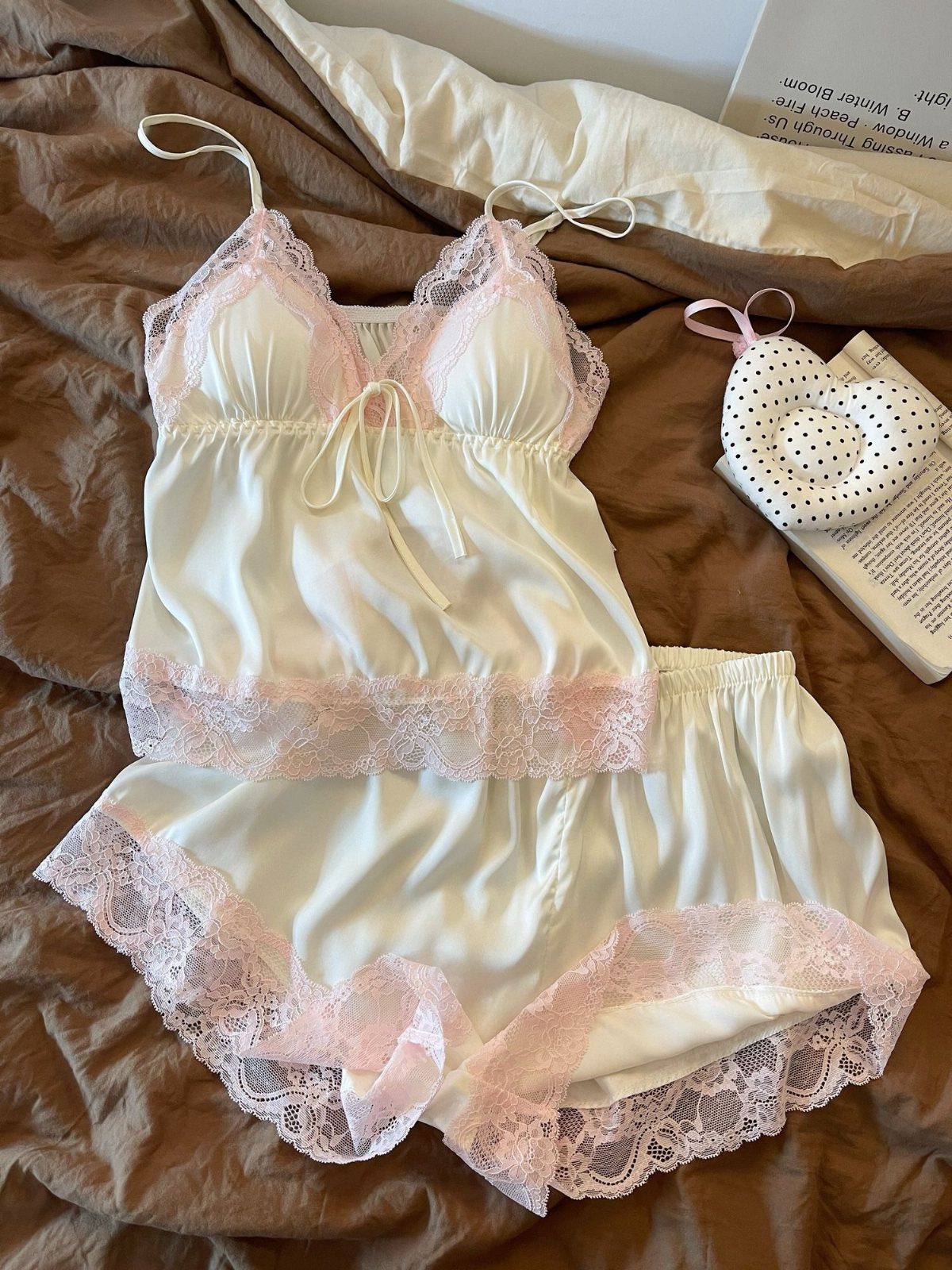 White satin pajama set with pink lace trim on brown fabric