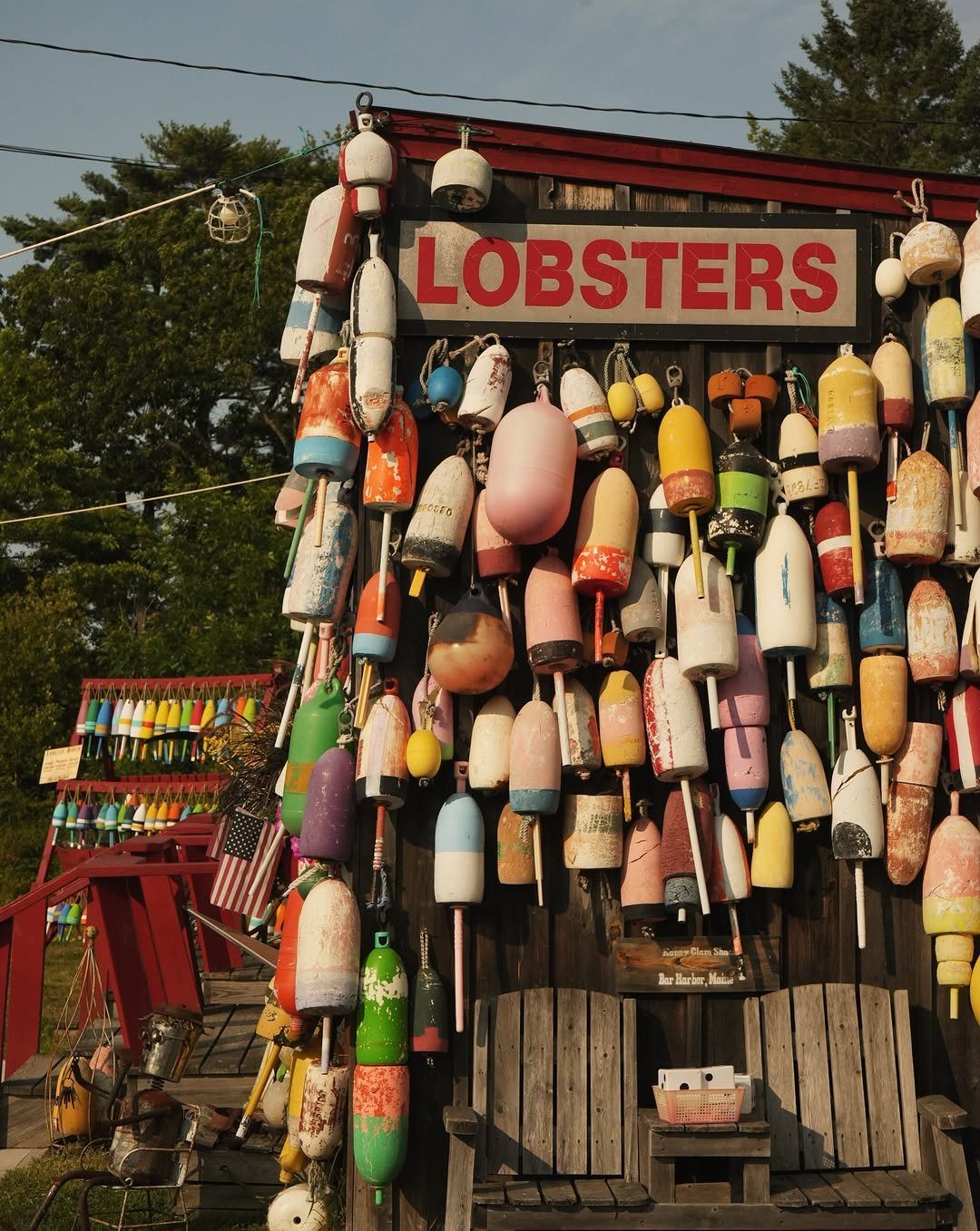 Colorful lobster buoys hanging on a wooden wall under a LOBSTERS sign.