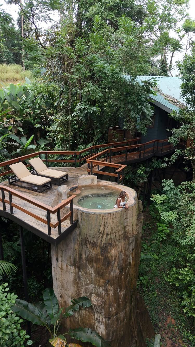 Luxury treehouse deck with lounge chairs and a hot tub in a tropical forest
