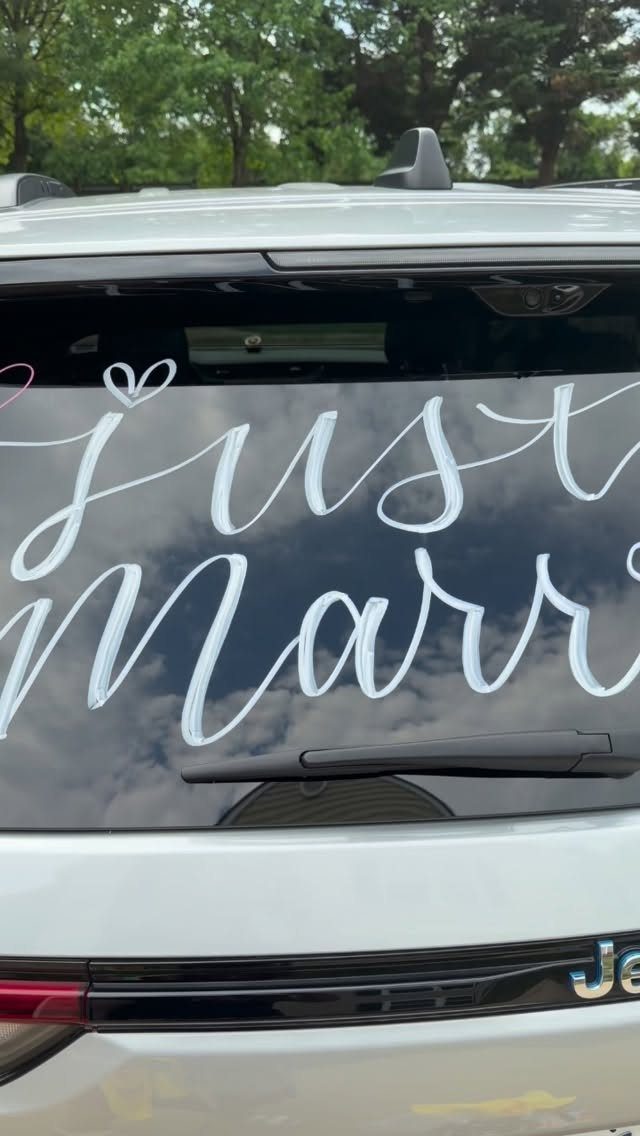 White cursive Just Married lettering on the rear window of a white car