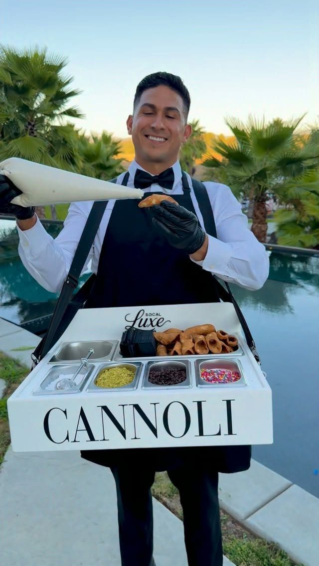 Waiter in formal attire preparing fresh cannoli from a tray by a pool